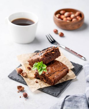 Fındıklı çikolatalı browni parçaları ve bir fincan kahveyle kabartma kağıdının üzerinde tuzlu karamel. Kahvaltıda lezzetli ve tatlı ev yapımı hamur işleri.. 
