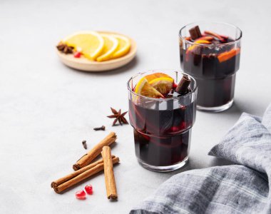 Hafif arka planda portakallı, elmalı ve tarçınlı sıcak şarap. Geleneksel, baharatlı ve meyveli sıcak kış içeceği konsepti..
