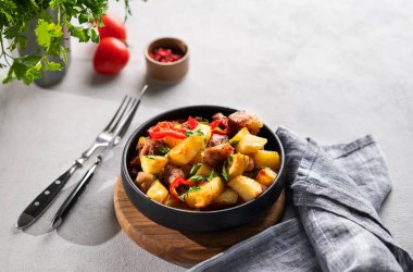 Patates, soğan ve biberli kızarmış domuz eti. Ulusal ev yapımı Gürcistan yemeği siyah bir kase içinde taze bitki, domates ve baharatlı. Metin için boş alan.
