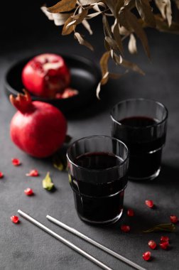 Karanlık bir arka planda bardakta taze meyve ve buketli doğal nar suyu. Vitaminli ve antioksidanlı taze sıkılmış sağlıklı bir içecek. Üst görünüm.