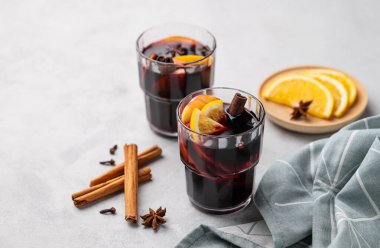 Hafif arka planda portakallı, elmalı ve tarçınlı sıcak şarap. Geleneksel, baharat ve meyveli sıcak kış içeceği kavramı. Metin için boş alan. 
