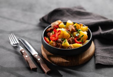 Patates, soğan ve biberli kızarmış domuz eti. Ulusal ev yapımı Gürcistan yemeği, siyah bir tavada gölgeli, siyah bir arka planda. Metin için boş alan.