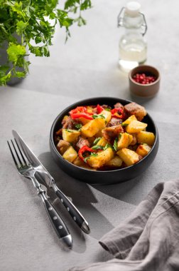 Patates, soğan ve biberli kızarmış domuz eti. Ulusal ev yapımı Gürcistan yemeği siyah bir kase içinde taze bitki ve baharatlarla birlikte.. 