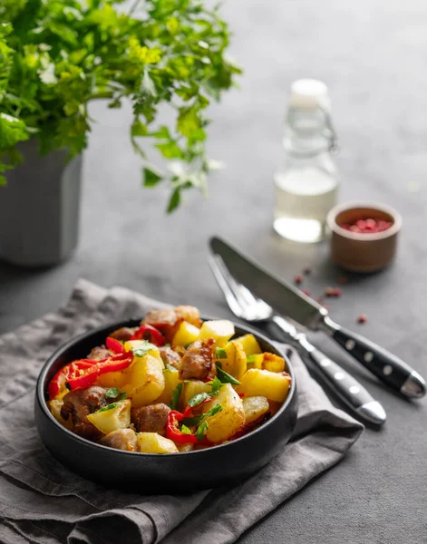 Patates, soğan ve biberli kızarmış domuz eti. Ulusal ev yapımı Gürcistan yemeği, siyah bir tavada, arka planda baharatlar ve taze bitkilerle birlikte yakın plan.. 