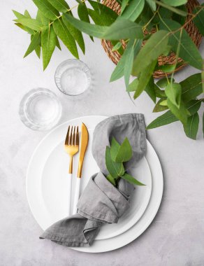 Beyaz tabaklar, gözlükler ve arka planda okaliptüs dalları olan bir peçete. Restoran menüsü konsepti. Üst görünüm.