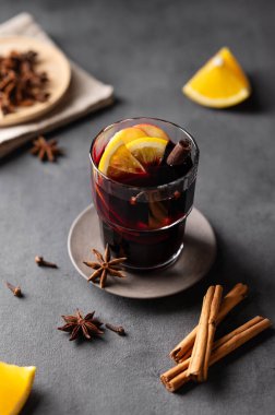 Koyu arkaplanda portakal, elma ve tarçınlı sıcak şarap. Geleneksel kış içeceği konsepti. Tatil için baharat ve meyveli..