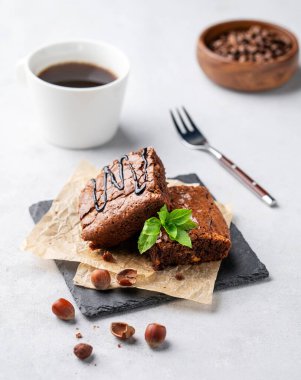 Fındıklı çikolatalı browni parçaları ve bir fincan kahveyle kabartma kağıdının üzerinde tuzlu karamel. Kahvaltıda lezzetli ve tatlı ev yapımı hamur işleri.