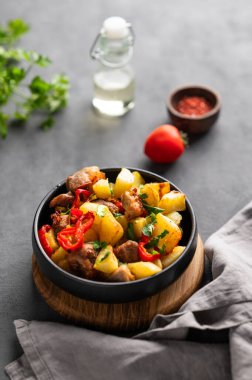 Patates, soğan ve biberli kızarmış domuz eti. Ulusal ev yapımı Gürcistan yemeği, siyah bir tavada, arka planda baharatlar, taze domatesler ve bitkilerle birlikte.. 