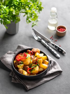 Patates, soğan ve biberli kızarmış domuz eti. Ulusal ev yapımı Gürcistan yemeği, siyah bir tavada, baharatlar ve taze bitkilerle kaplanmış. Üst görünüm.