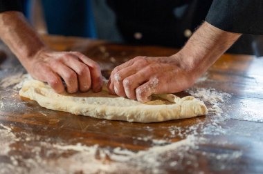 Ahşap bir masada Adjarian Khachapuri için hamur yoğuran ellerin yakın çekimi..
