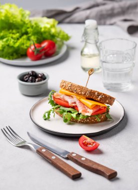 Çedar peynirli tahıllı ekmek ve domates ve roka ile doldurulmuş domuz pastırmalı tost kulübü sandviçi. Sağlıklı ve beslenme kahvaltısı kavramı. 