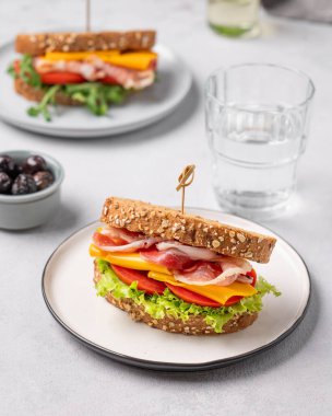 Çedar peynirli buğday ekmeğinden yapılmış iki tost kulübü sandviçi ve domatesli pastırma, zeytinli marul. Sağlıklı ve beslenme kahvaltısı kavramı. 