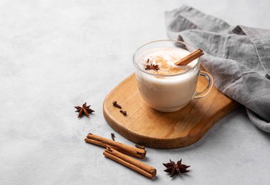 Geleneksel Hint masala chai latte 'si. Sütlü, baharatlı ve otlu sıcak içecek, arka planda tahta bir tahta üzerinde. Metin için boş alan.