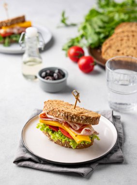 Domuz pastırmalı, peynirli, domatesli ve zeytinli, otlu ve bir bardak suyla marullu sandviç. Kahvaltıda veya öğle yemeğinde sağlıklı atıştırmalık konsepti.