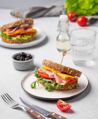 Çedar peynirli tahıllı ekmek ve domates ve roka ile doldurulmuş domuz pastırmalı tost kulübü sandviçi. Sağlıklı ve beslenme kahvaltısı kavramı. 