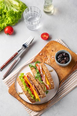 Domuz pastırmalı, peynirli, domatesli ve marullu sandviç ve zeytinli ve bir bardak suyla. Kahvaltıda ya da öğle yemeğinde sağlıklı atıştırmalık konsepti. Üst görünüm.