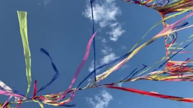 Çok renkli kurdeleler ya da çelenkler, güneşli bir yaz gününde bulutlu mavi gökyüzü ile rüzgarda sallanır. Dini törenler için şenlikli bir dekorasyon konsepti. Yoga festivaline geri çekilin..
