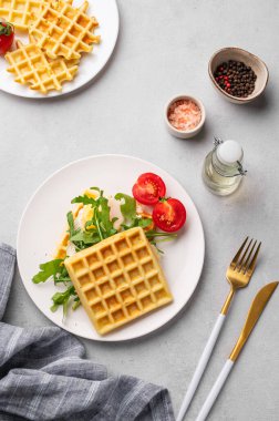 Yağda yumurta, vişneli domates ve roka ile birlikte gri dokuma arka planında beyaz bir tabakta baharatlar ve peçeteyle. Sağlıklı ve lezzetli kahvaltı kavramı. Üst görünüm.