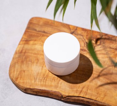 Vücut ve yüz için organik kozmetik kremi. Tahta bir tahtanın üzerinde yeşil yapraklı bir kavanozda. Spa güzellik konsepti doğal ürün. Üst görünüm.