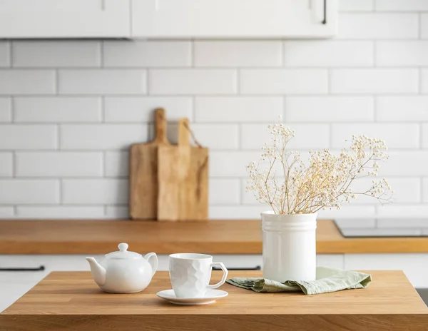 木制橡木桌子 有一杯茶 一个水壶和干燥的花朵在厨房前面的一个花瓶 白色的砖背景 斯堪的纳维亚风格的舒适早餐概念 — 图库照片