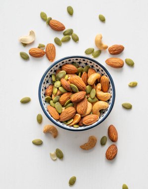 Fındık karışımı. Badem, kaju ve kabak tohumları beyaz ahşap arka planda bir kasede. Sağlıklı enerji atıştırmalığı konsepti. Üst görünüm.