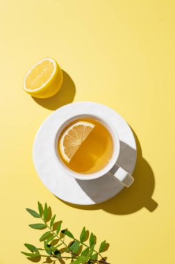 Sarı arka planda beyaz bardakta limonlu bitki çayı. Dokunulmazlık için detoks içeceği konsepti. Üst görünüm ve kopyalama alanı.