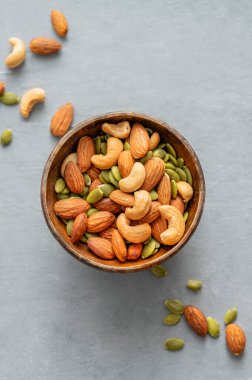 Fındık karışımı. Badem, kaju ve kabak tohumları ahşap bir kasede mavi arka planda. Sağlıklı enerji atıştırmalığı konsepti. Üst görünüm ve kopyalama alanı.