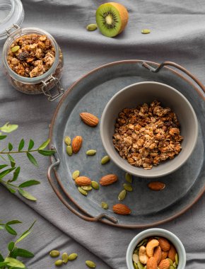 Kavanozda ev yapımı tahıl gevreği ve fındık ve meyveli koyu keten arka planda bir kase. Rahatlatıcı yemek. Kahvaltıda sağlıklı ve besleyici tahıl müsli konsepti. Üst görünüm.