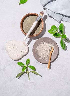 El yapımı kozmetik. Arka planda hafif bir fırçayla gölgeli ve yapraklı bir kasede organik kil. Yüz ve vücut için bir maske hazırlama kavramı. Üst görünüm ve kopyalama alanı.