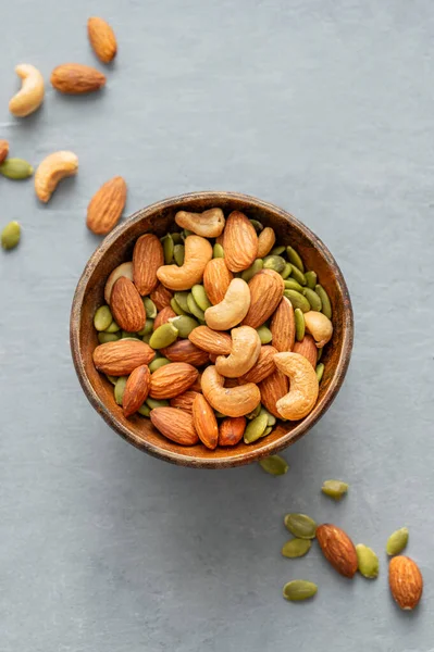 Fındık karışımı. Badem, kaju ve kabak tohumları ahşap bir kasede mavi arka planda. Sağlıklı enerji atıştırmalığı konsepti. Üst görünüm ve kopyalama alanı.