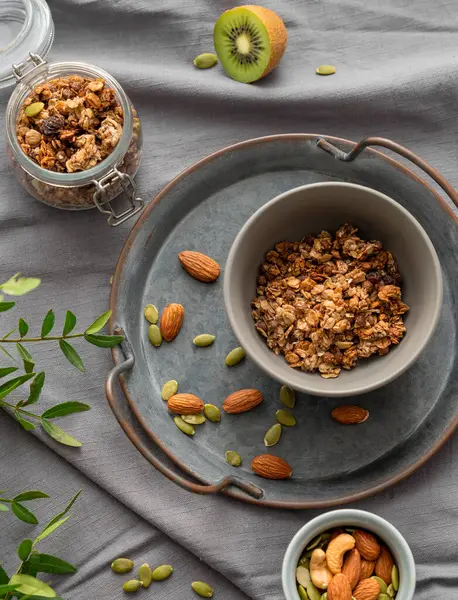 Kavanozda ev yapımı tahıl gevreği ve fındık ve meyveli koyu keten arka planda bir kase. Rahatlatıcı yemek. Kahvaltıda sağlıklı ve besleyici tahıl müsli konsepti. Üst görünüm.