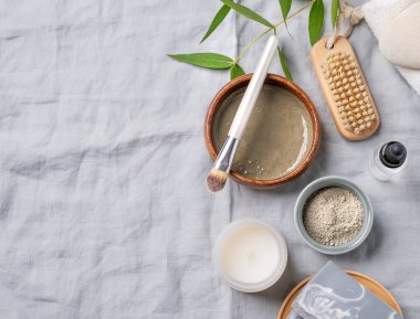 Mavi kil, sabun, fırça, mum ve hafif keten arka planda dallı organik kozmetik. Ev yapımı cilt bakım ürünleri hazırlama konsepti. Üst görünüm ve kopyalama alanı.