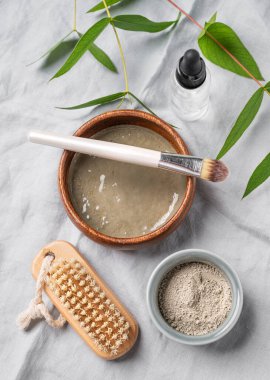 Mavi kil, hafif keten arka planda fırça ve dal. Ev yapımı cilt bakımı organik kozmetik ürünleri. Üst görünüm.