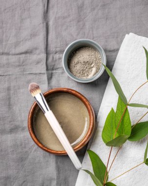 Mavi kil, fırça, havlu ve çarşaf üzerine dallı organik kozmetik. Ev yapımı cilt bakım ürünleri hazırlama konsepti. Üst görünüm ve kopyalama alanı.