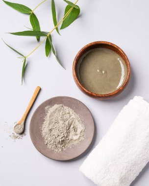 Havlu ve dallı hafif arka planda bir kasede mavi kil. Ev yapımı cilt bakımı organik kozmetik ürünleri. Üst görünüm.