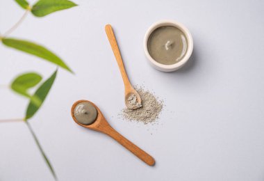 Kasede mavi kil ve arka planda dallı kaşıklar. Ev yapımı cilt bakımı organik kozmetik ürünleri ve spa tedavisi için konsept. Üst görünüm ve kopyalama alanı.