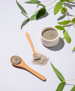 Kasede mavi kil ve arka planda dallı kaşıklar. Ev yapımı cilt bakımı organik kozmetik ürünleri ve spa tedavisi. 