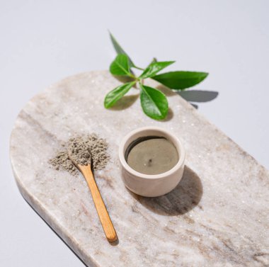 Mavi kil bir kasede ve kaşık misket tahtasının üzerinde, arka planda yapraklarla. Ev yapımı cilt bakımı organik kozmetik ürünleri ve spa tedavisi. 