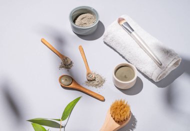 Hafif arka planda, havlu, fırça ve gölgeli bir kaşıkta mavi kil. Ev yapımı cilt bakımı organik kozmetik ürünleri ve spa tedavisi. 