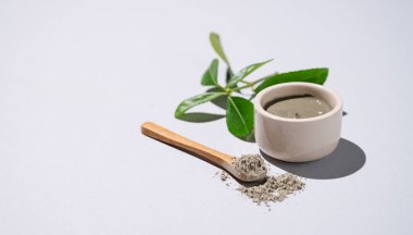 Kasede mavi kil ve arka planda yapraklı kaşık. Ev yapımı cilt bakımı organik kozmetik ürünleri ve spa tedavisi için konsept. Boşluğu kopyala.