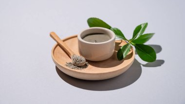 Mavi kil bir kase içinde ve kaşık tahta bir tabakta, arka planda yapraklar ve gölgelerle. Ev yapımı cilt bakımı organik kozmetik ürünleri ve spa tedavisi için konsept. Boşluğu kopyala.