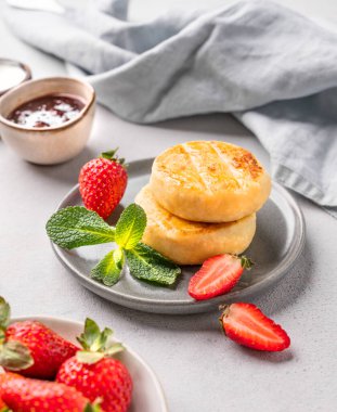 Süzme peynir, peynirli kek ya da çilekli şurup, hafif arkaplanlı gri bir tabakta çilek reçeli ve nane yaprağı. Besleyici ve sağlıklı kahvaltı kavramı.. 