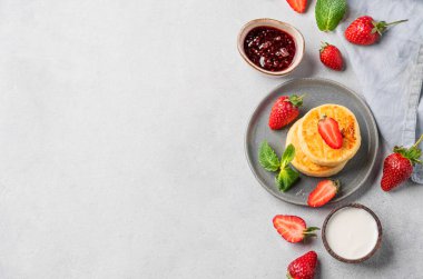 Süzme peynir, peynirli kek ya da ekşi krema, reçel, çilek ve nane yapraklı şurup. Besleyici ve sağlıklı kahvaltı kavramı.. 