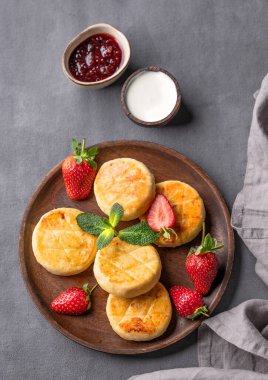 Süzme peynir, peynirli kek ya da ekşi krema, reçel, çilek ve nane yapraklı şurup. Besleyici ve sağlıklı kahvaltı kavramı.. 