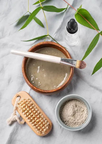 Mavi kil, hafif keten arka planda fırça ve dal. Ev yapımı cilt bakımı organik kozmetik ürünleri. Üst görünüm.