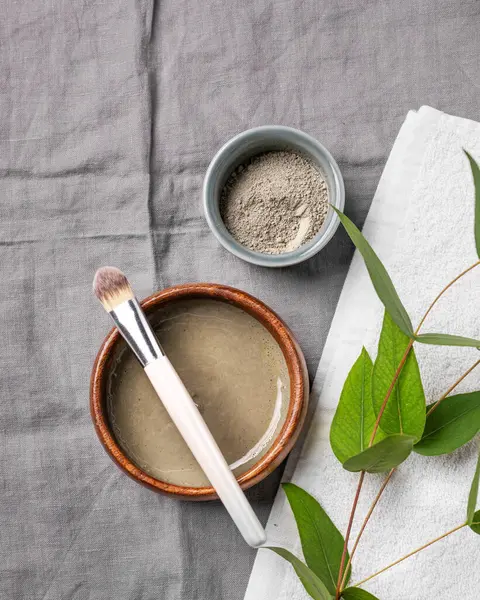 Mavi kil, fırça, havlu ve çarşaf üzerine dallı organik kozmetik. Ev yapımı cilt bakım ürünleri hazırlama konsepti. Üst görünüm ve kopyalama alanı.