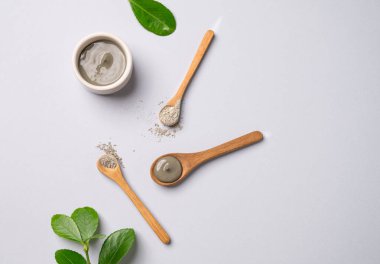 Kasede mavi kil ve arka planda yapraklı kaşıklar. Ev yapımı cilt bakımı organik kozmetik ürünleri ve spa tedavisi için konsept. Üst görünüm ve kopyalama alanı.