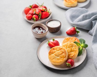 Süzme peynir, peynirli kek ya da çilekli şurup, ekşi krema, reçel ve nane yaprağı beyaz bir tabakta peçeteyle birlikte. Sağlıklı kahvaltı kavramı. Boşluğu kopyala.