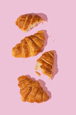 Pembe arka planda gölgeli taze kruvasanlar. Yaratıcı tasarım ve sağlıklı yemek ve Fransız kahvaltısı konsepti. Üst görünüm. 