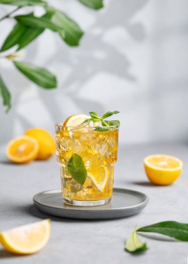 Limonlu buzlu çay, naneli ve buzlu. Arka planda gölgesi ve dalı olan bir bardakta. Sıcak bir yaz gününde ferahlatıcı içecek ya da limonata konsepti. 